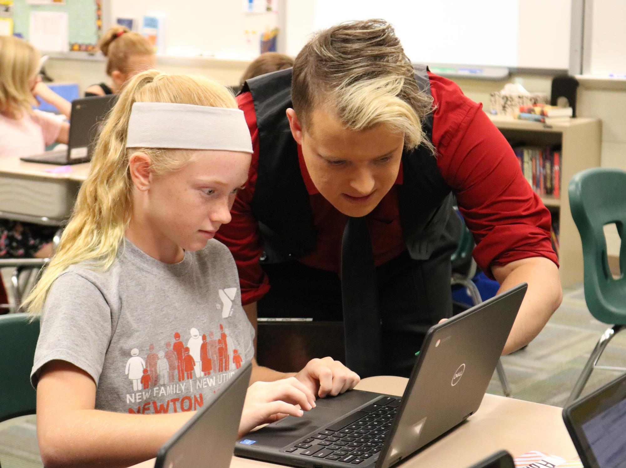 Teacher helping middle school student at computer