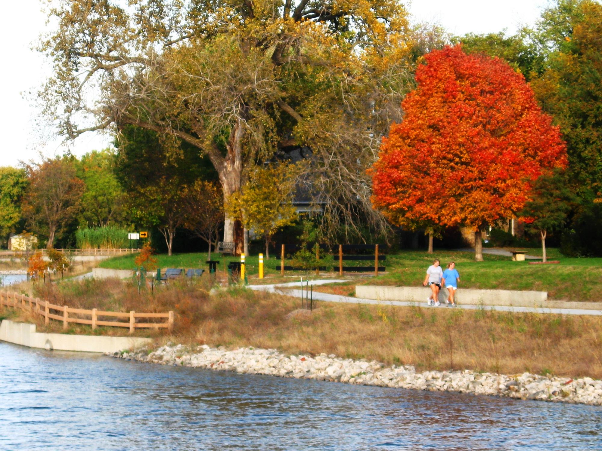 Two women walking on trail next to Sand Creek